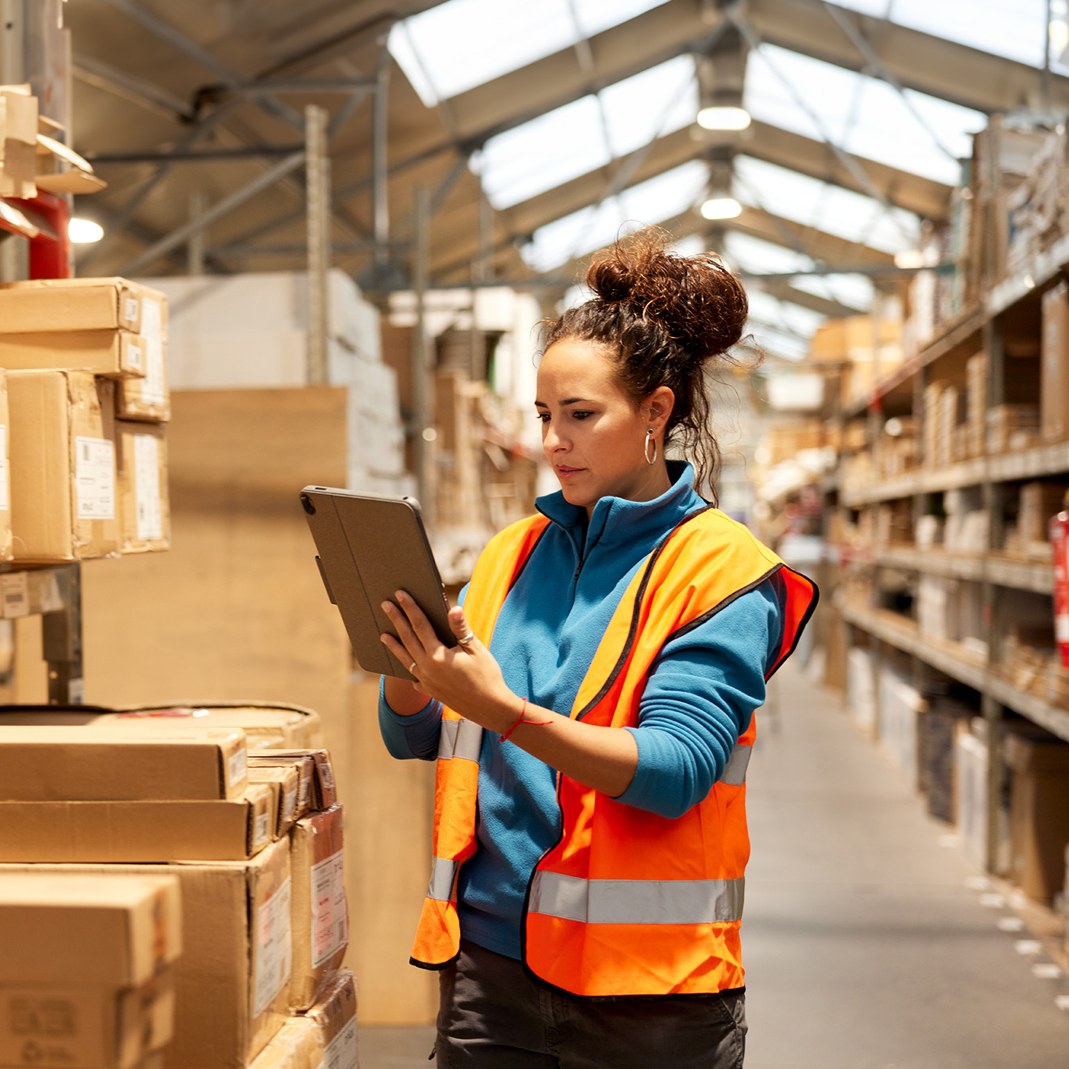A warehouse worker takes inventory in the storage room standing next to a shelf and using a digital tablet. - stock photo