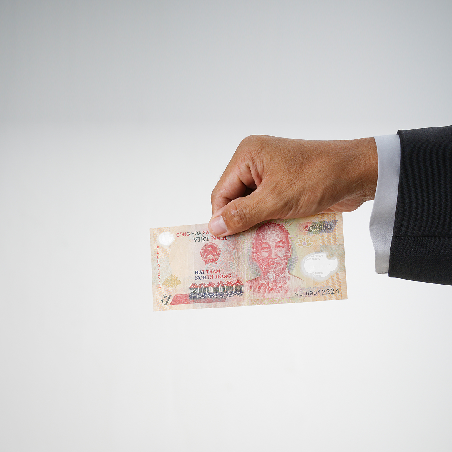 Cropped hand holding Vietnam banknotes on white background.  - stock photo