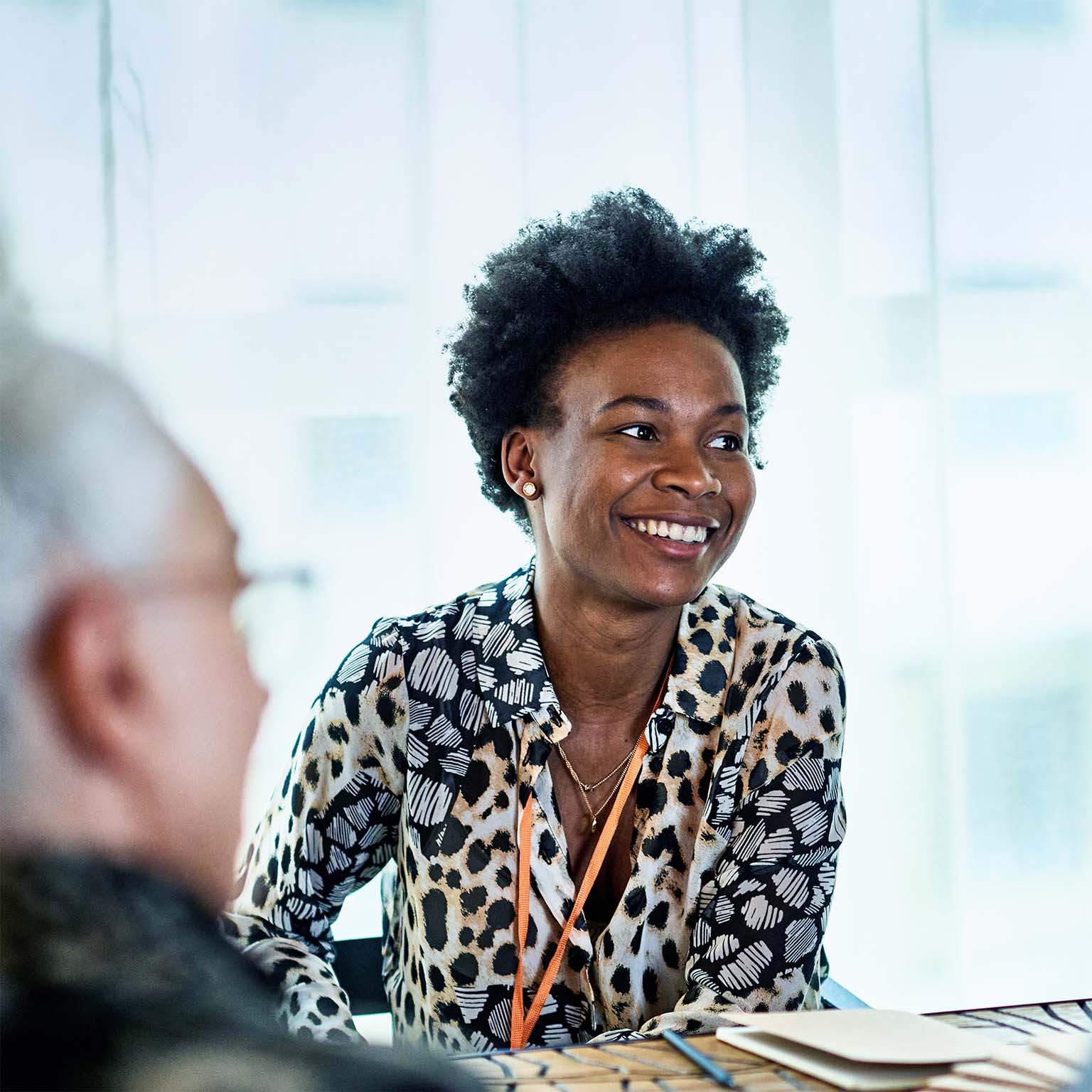 Cheerful woman in her 30s in business meeting with colleagues, smiling and listening, confidence, expertise, team player