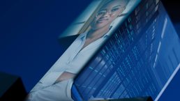 Projected image of young, professional woman, with arms crossed, building the next big thing.