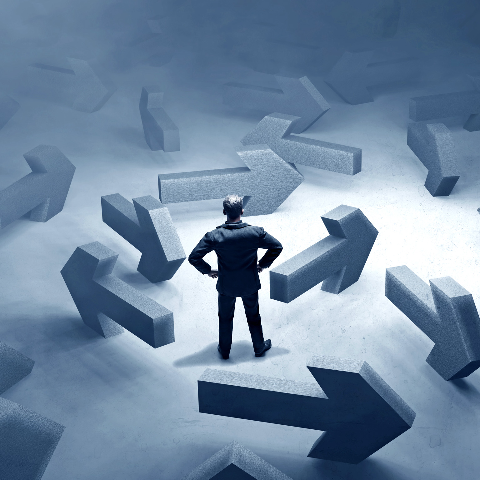 A multitude of large, concrete arrows pointing in different directions surround a businessman.