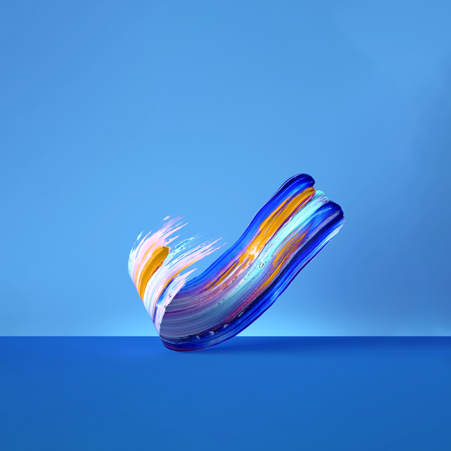  Against a vivid blue background, a vibrant, multicolor brushstroke of paint gracefully curves upwards.