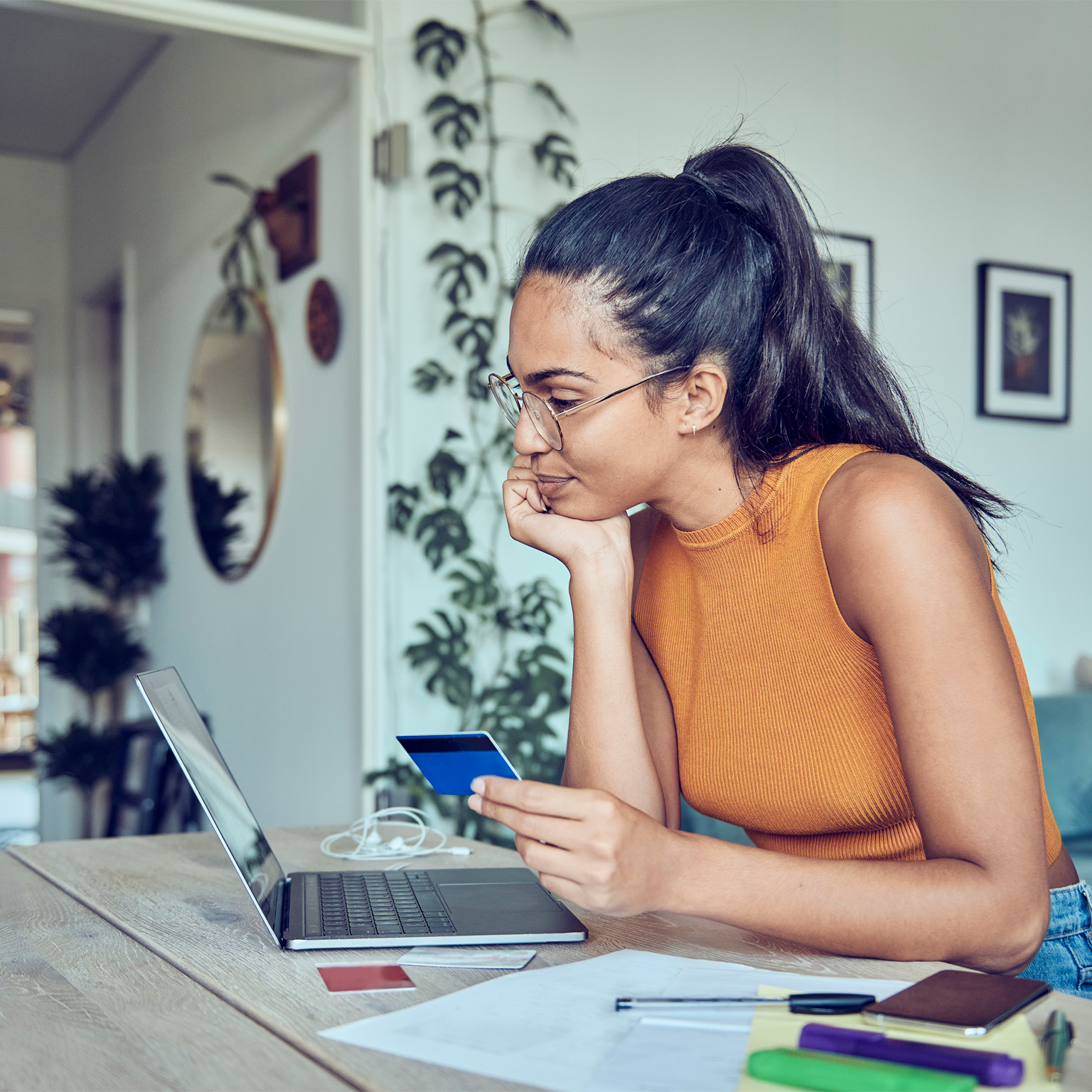 photo woman in apartment online shopping on laptop with credit card in hand 