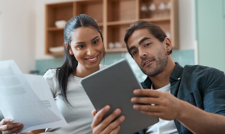 Shot of a young couple doing paperwork while using a digital tablet at home