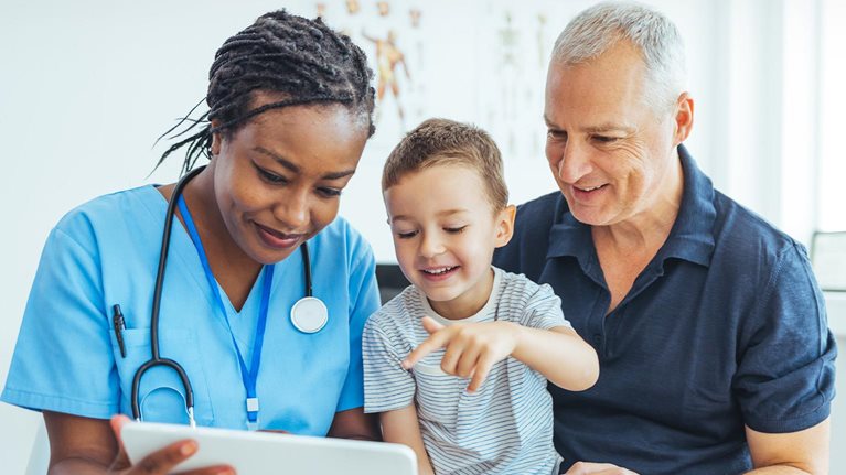 Female pediatrician doctor showing father medical results on tablet in clinic.