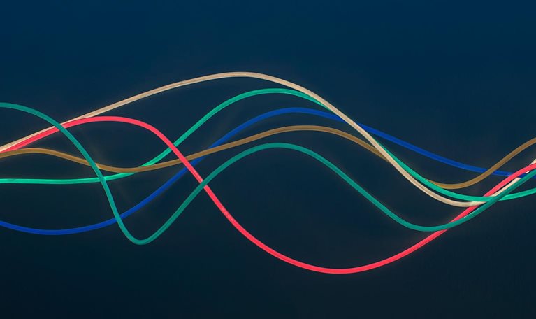 Blue, green, red, brown and white wire in wave pattern on dark blue background - stock photo