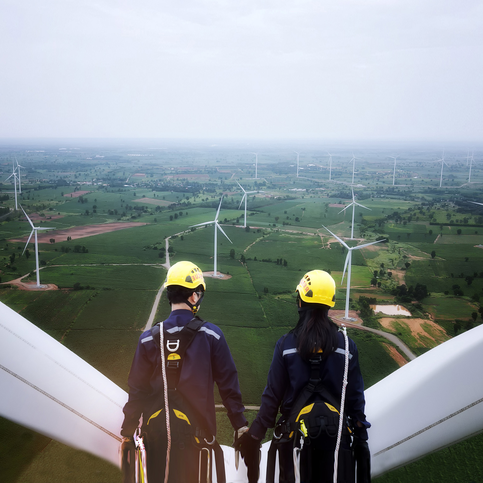 photo man and woman standing on top of wind turbine