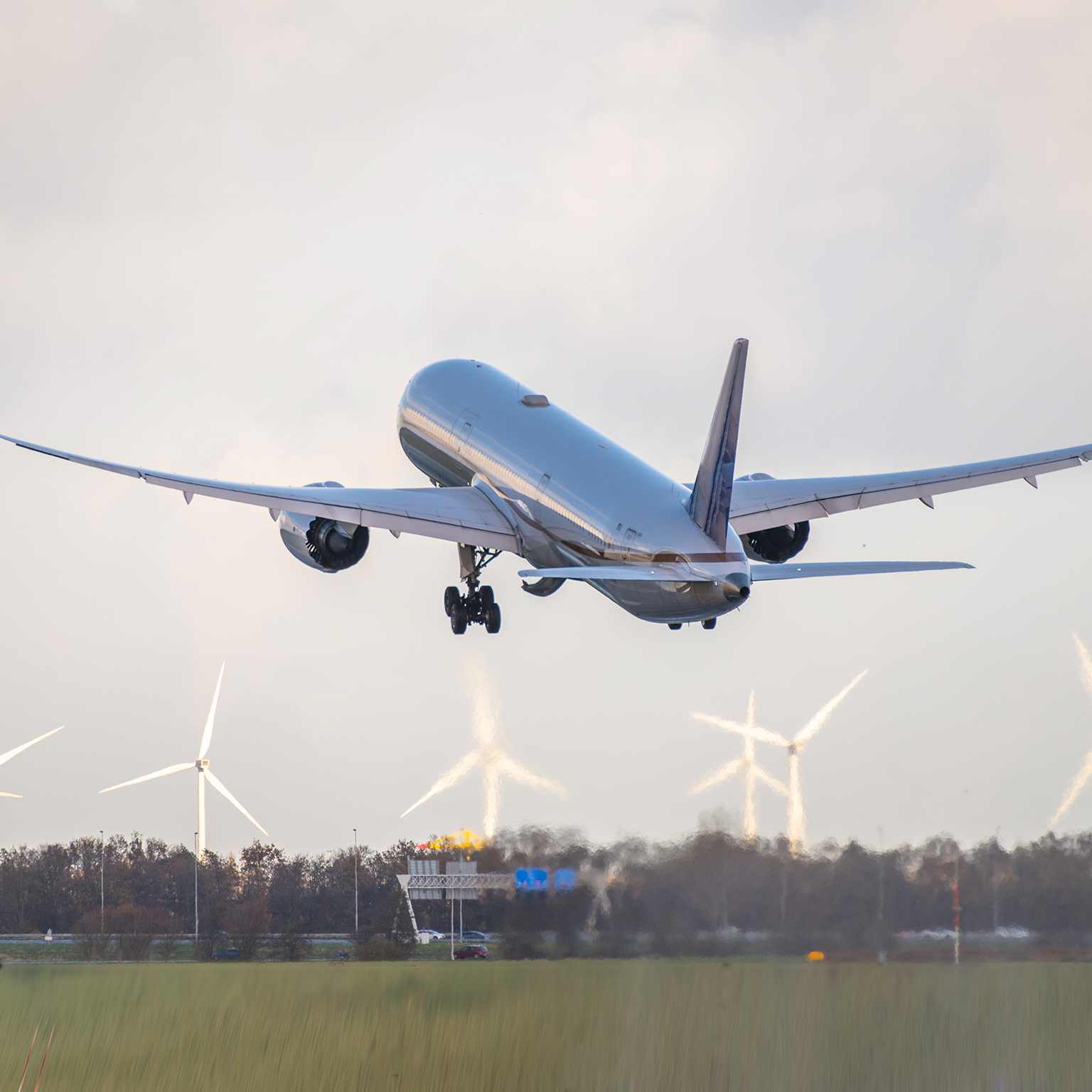 plane taking off with wind turbines in background stock photo