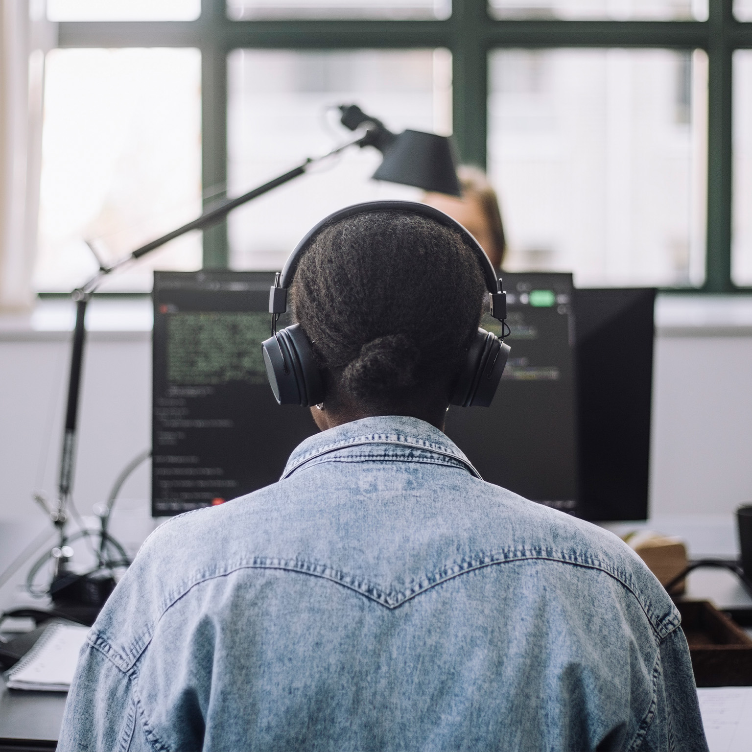 Rear view of female computer programmer coding on computer at desk in office - stock photo