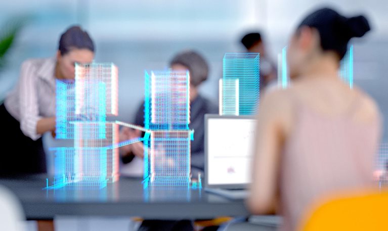 Team collaborating at a table with digital holographic models of buildings displayed in front of them.
