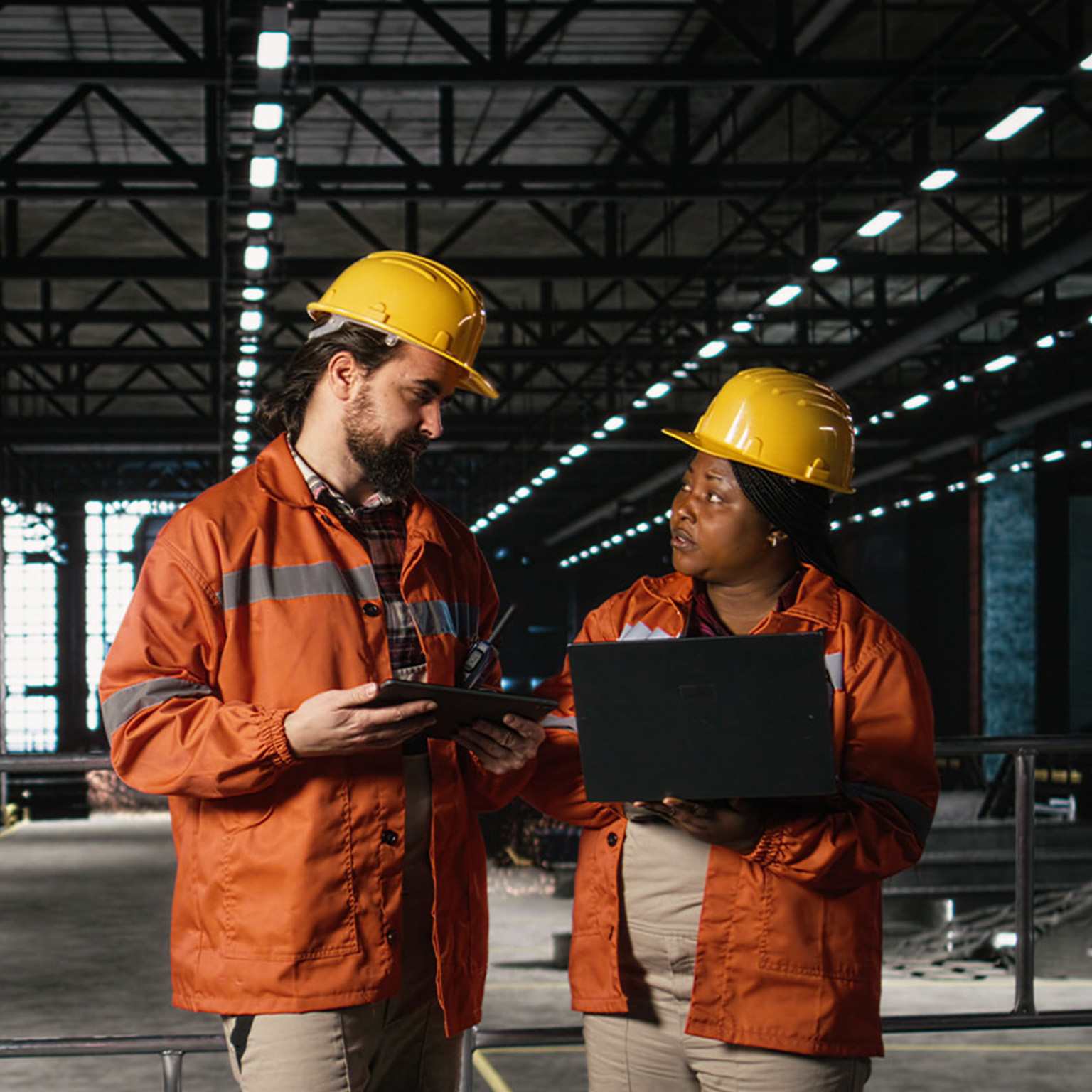 Engineering team reviewing steel work and heavy equipment in industrial space