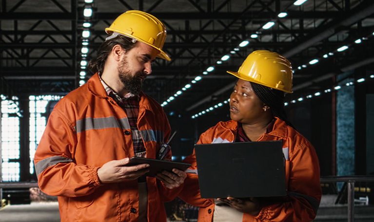 Engineering team reviewing steel work and heavy equipment in industrial space