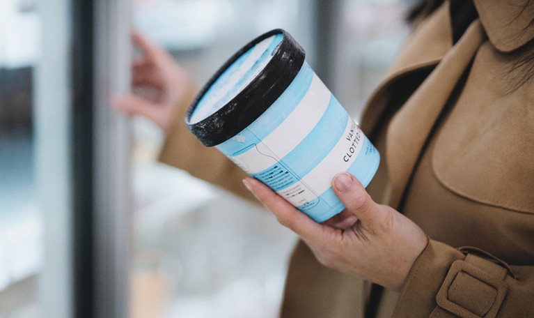 Woman holding a cup of vanilla ice cream in supermarket