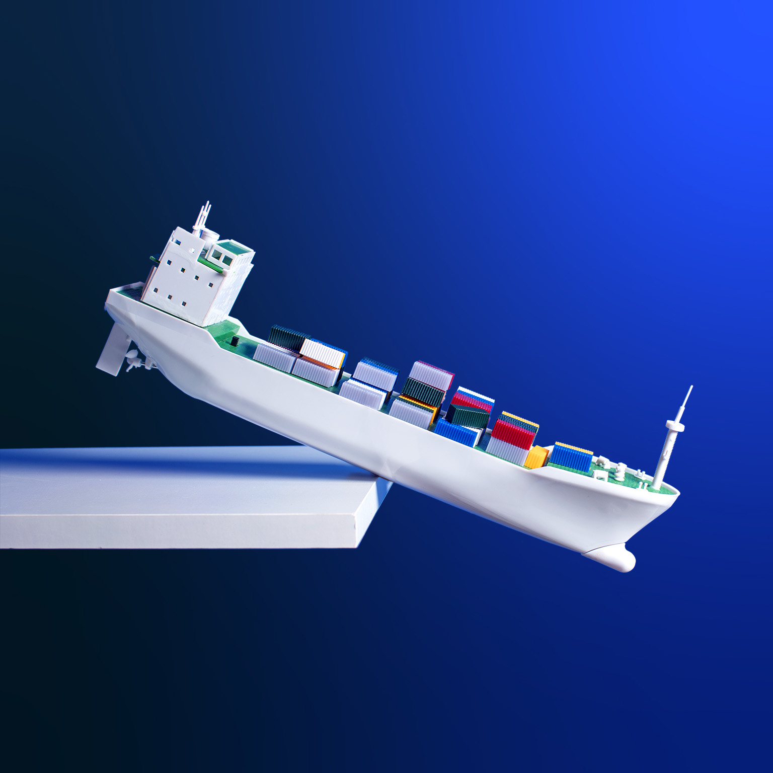 An conceptual image of a toy container ship with multi-colored containers teetering on the edge of a shelf.