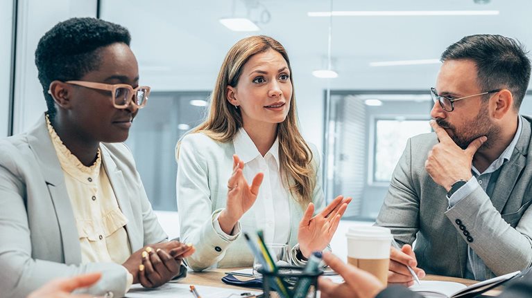 Modern business team smiling and talking in board room discussing new ideas at the office.