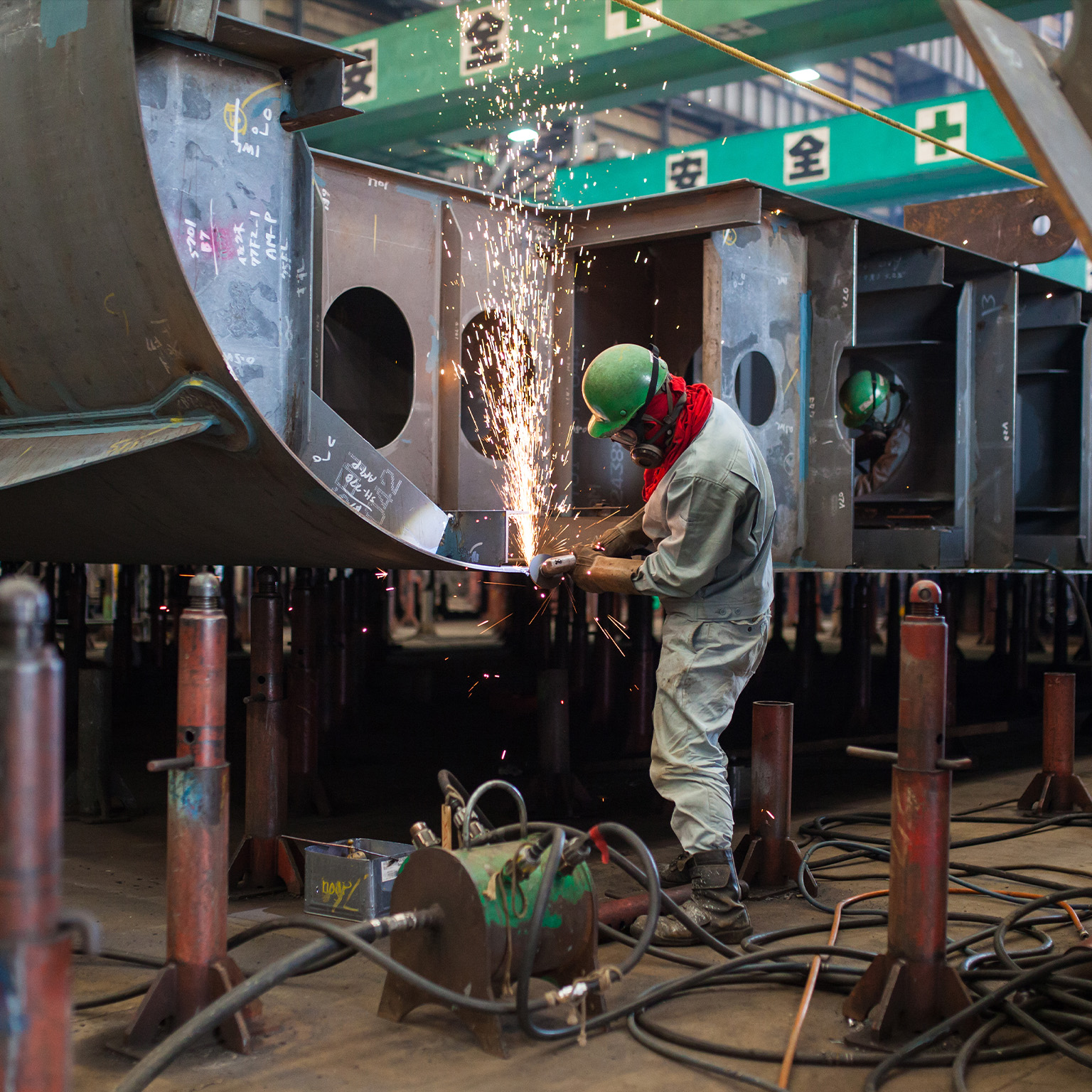 A man welding inside a shipbuilding factory - stock photo