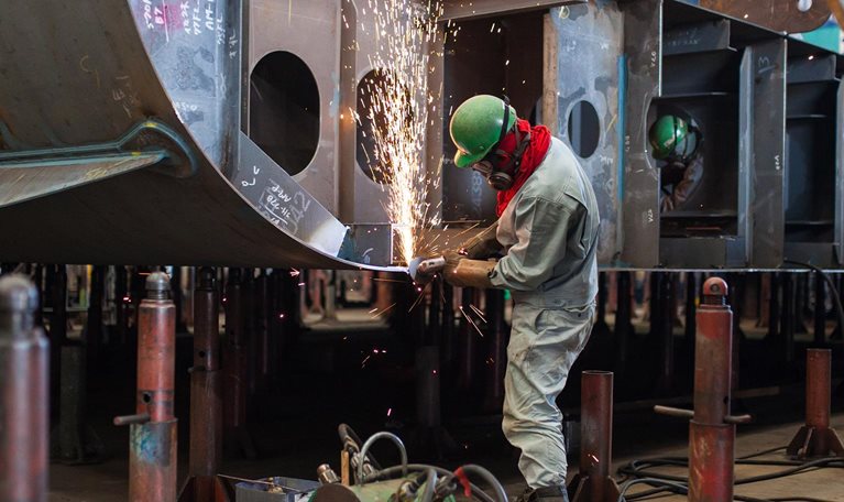A man welding inside a shipbuilding factory - stock photo