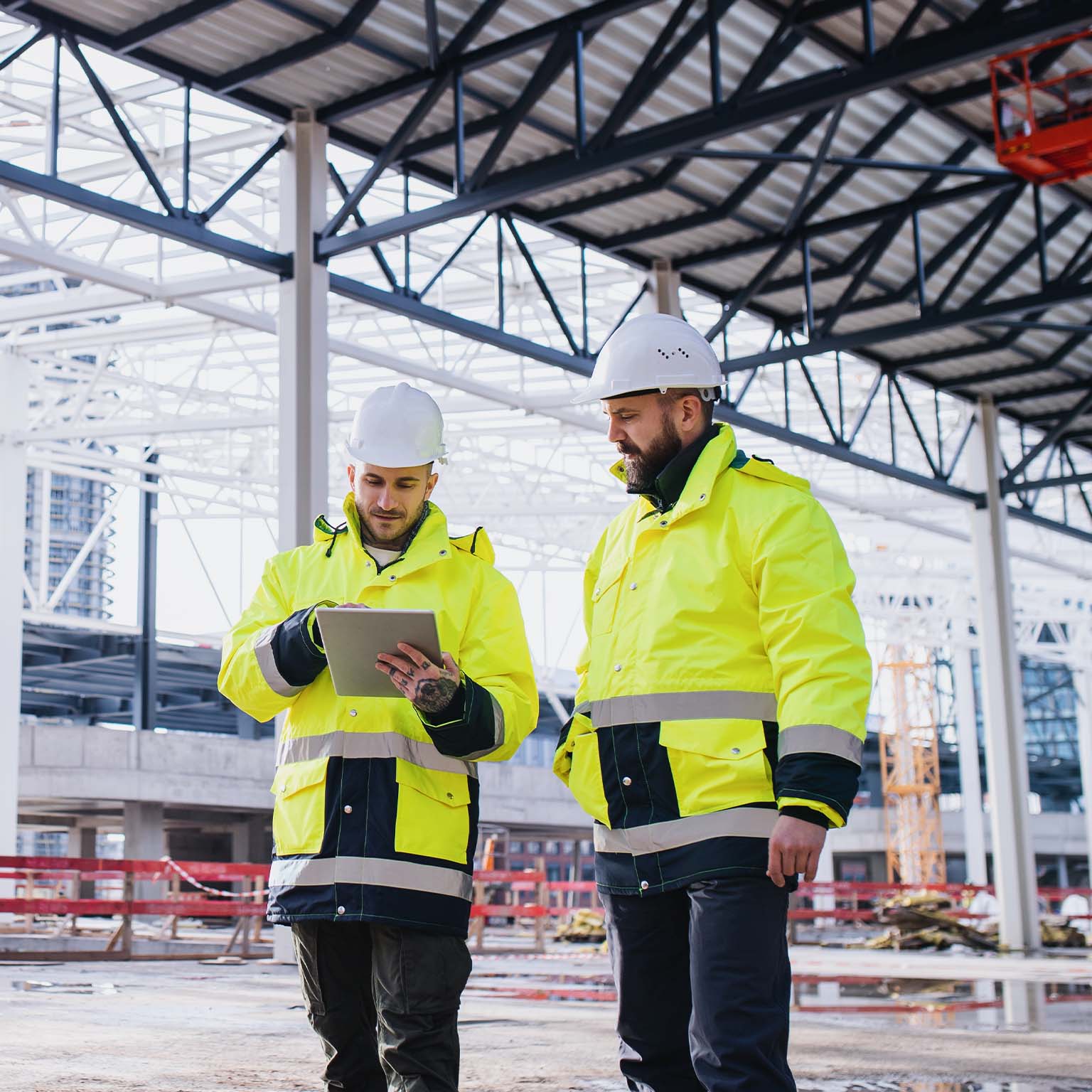 Engineers standing outdoors on construction site, using tablet.