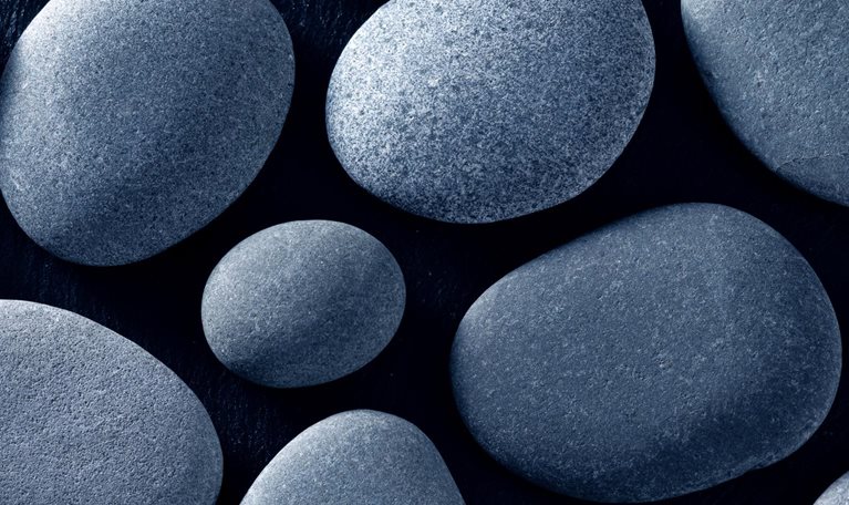 Smooth, gray river stones on a black background.