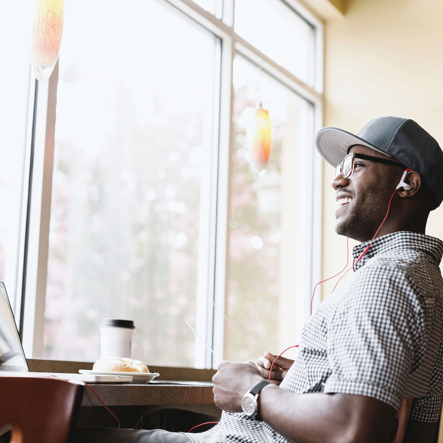 Laughing man using laptop in coffee shop
