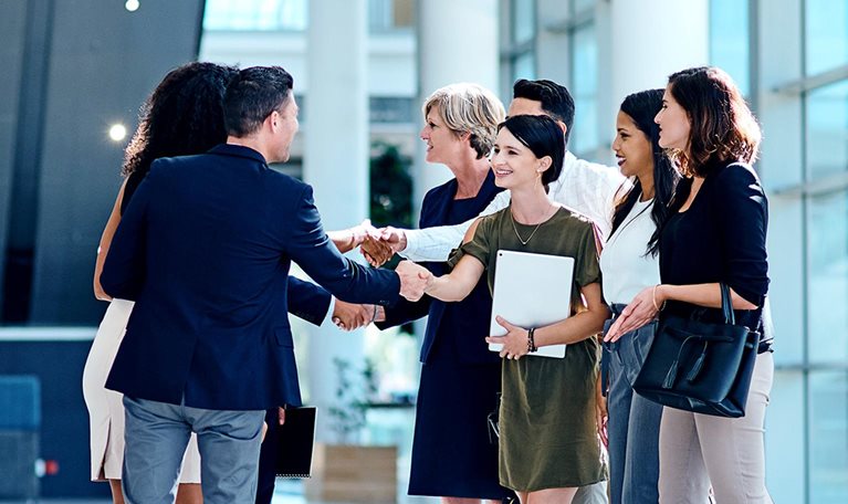 A group of businesspeople greeting each other inside of a office