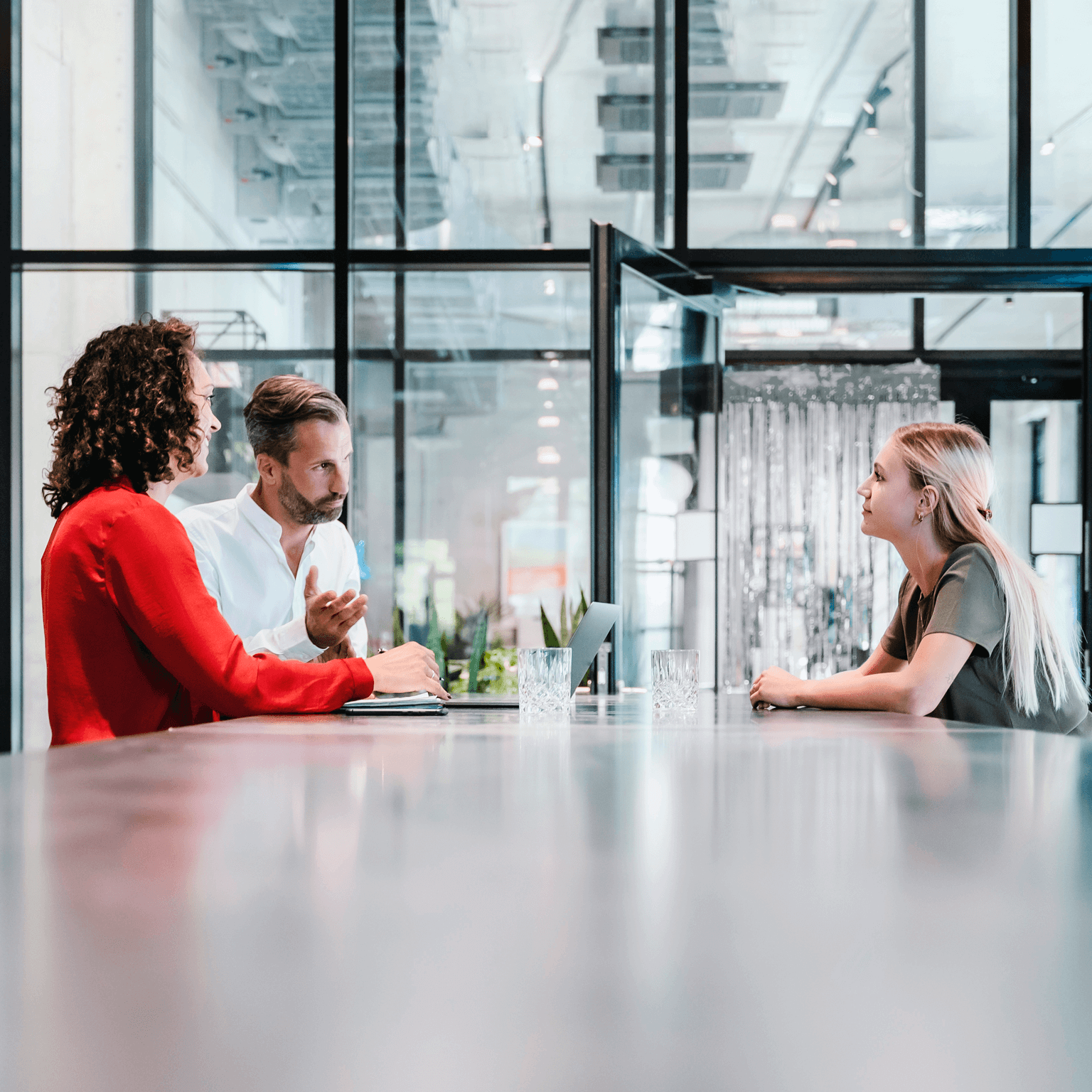 Three people converse at a desk