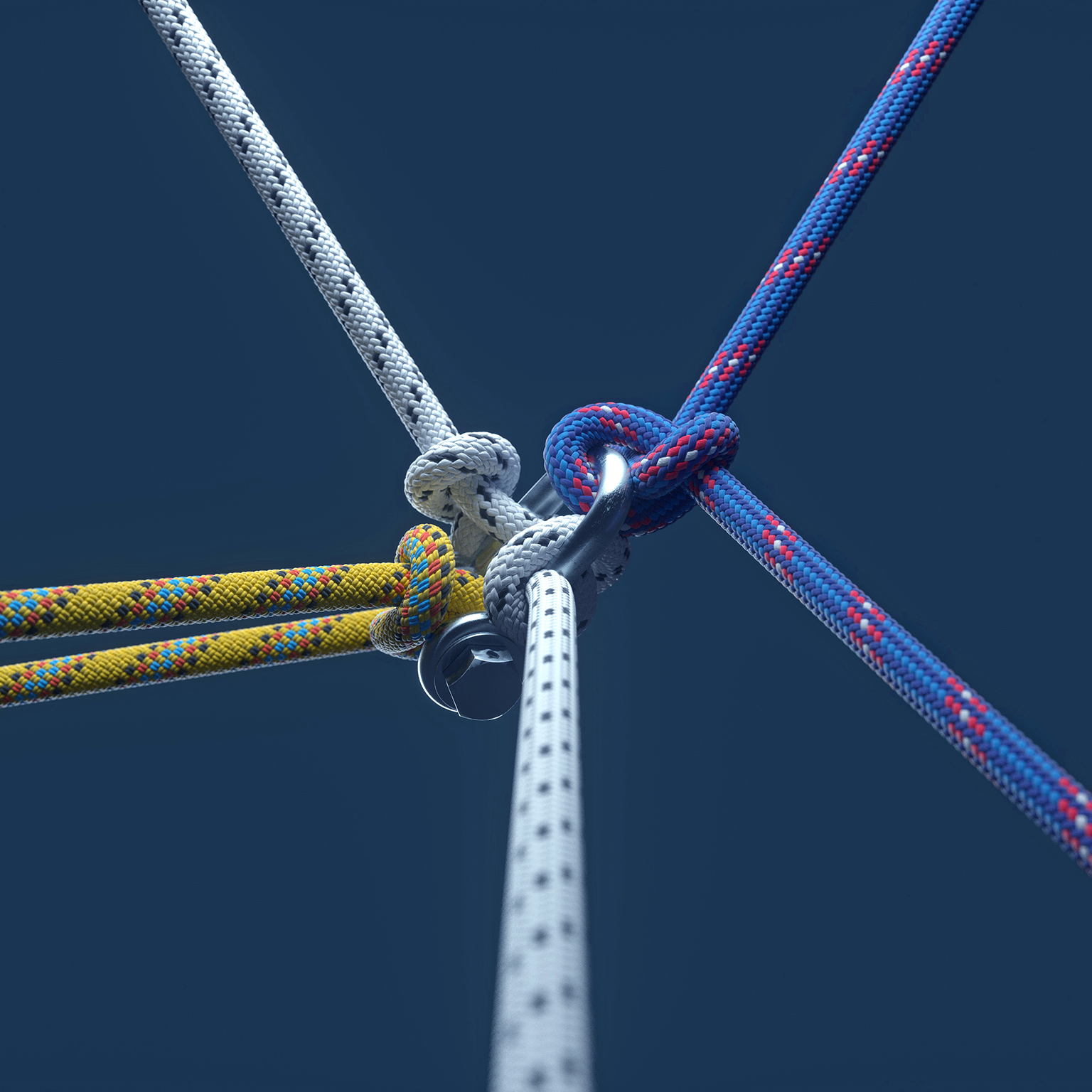 Close-up image of three colored ropes knotting together on dark blue background.