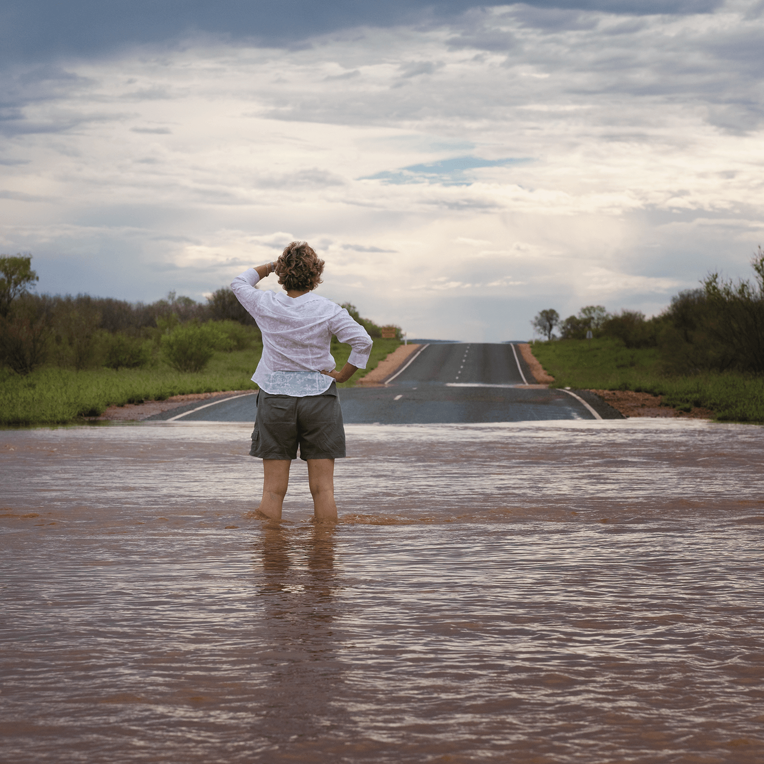 Woman stands in flooded street.
