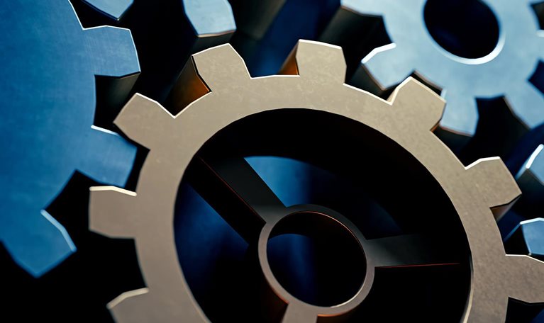 Shadowed image of blue and gold gears moving in a machine