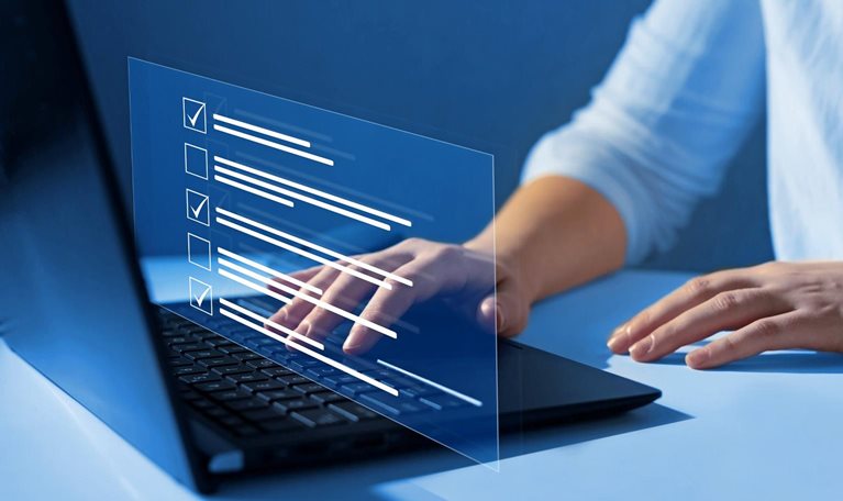 Close up of a woman's hands on a laptop keyboard. A representation of a screen display floats over her hands showing boxes getting checked off as she answers quiz questions.