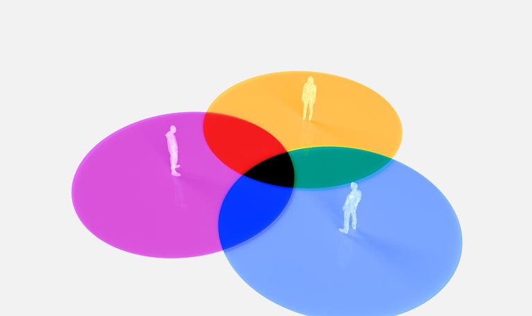 Three translucent circles, each in a different color (purple, yellow, and blue) that bring to mind a venn diagram. Inside each circle stands a small human figure.