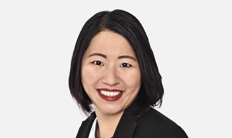 Portrait of Marjorie Lao with a bright smile and wearing a suit jacket over a fine knit top.