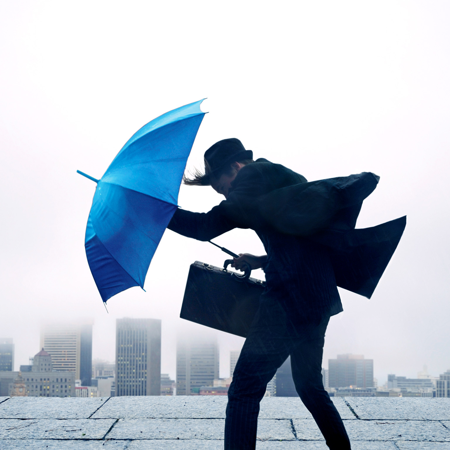 Businessman with umbrella in the wind