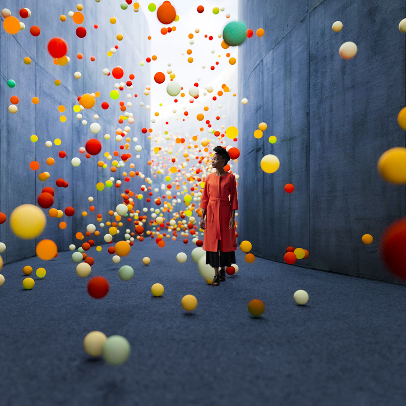 Woman walking in abstract concrete corridor with large amount of exploding spheres.