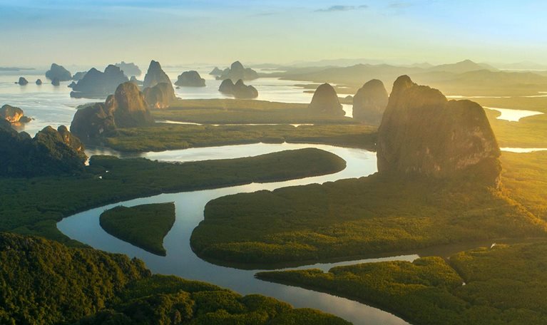 A horizon line view of the limestone cliffs and rock formations of Phang Nga Bay in Thailand.