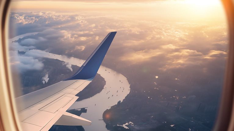 This image captures a breathtaking moment in time, showing a scenic view from an airplane window during sunset.
