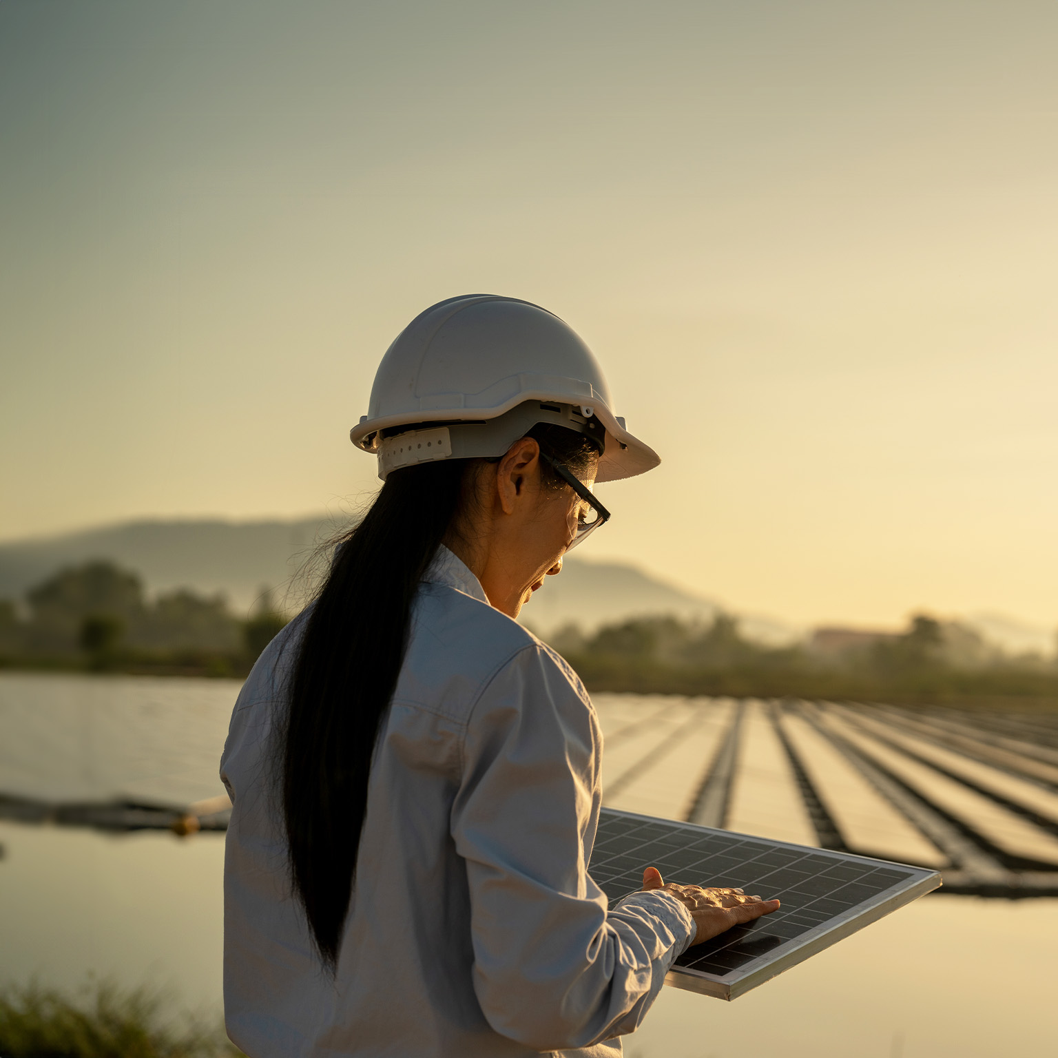 Female Asian engineer handle solar panel working on site of a floating solar farm.