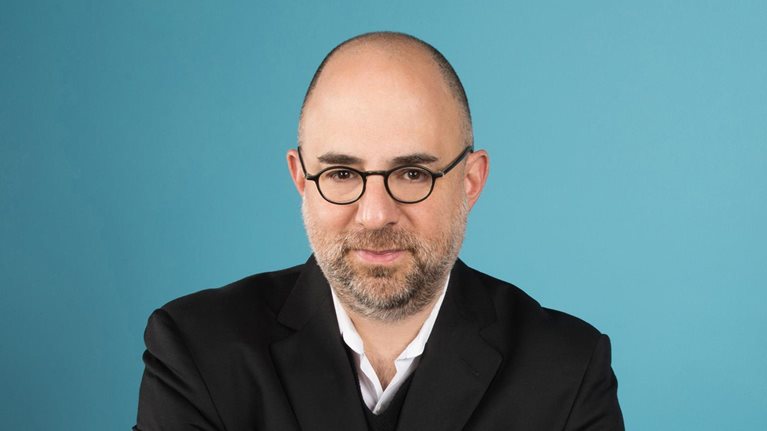 Portrait of Moshik Temkin in front of a teal backdrop.