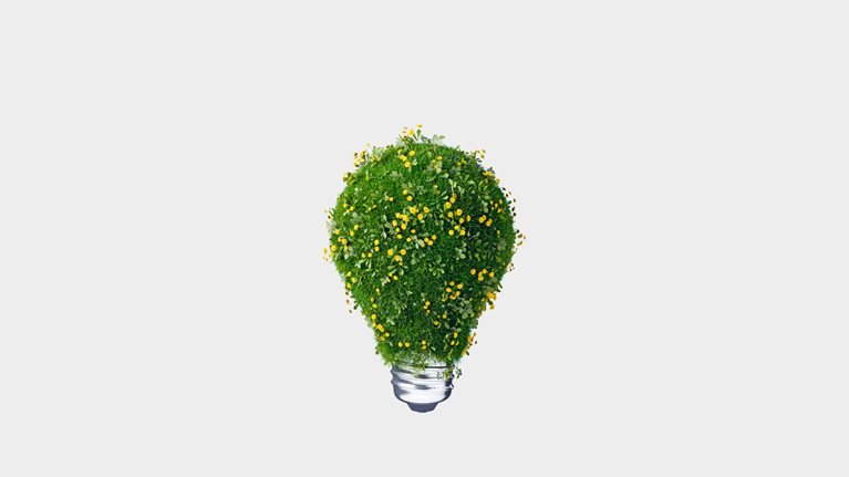 A 3D rendering of light bulb covered with green grass and blooming yellow flowers against light gray background