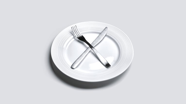 Empty plate with knife and fork in cross shape