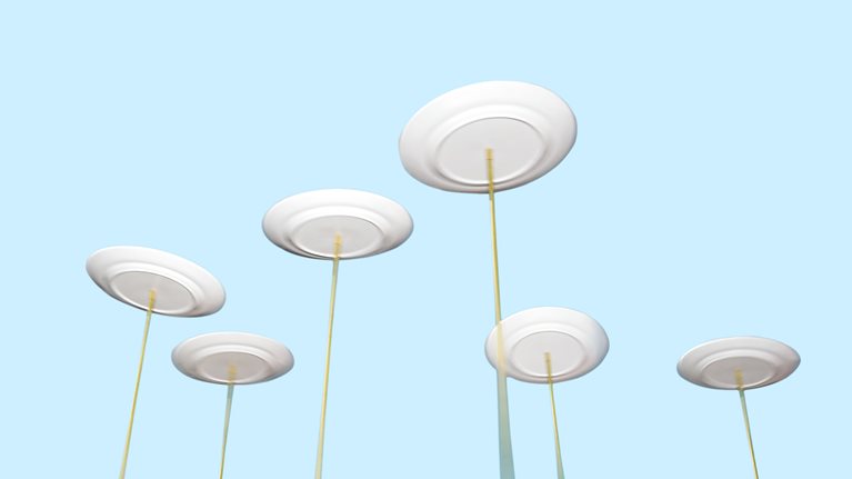 Spinning plates balancing on long poles against a light blue background.