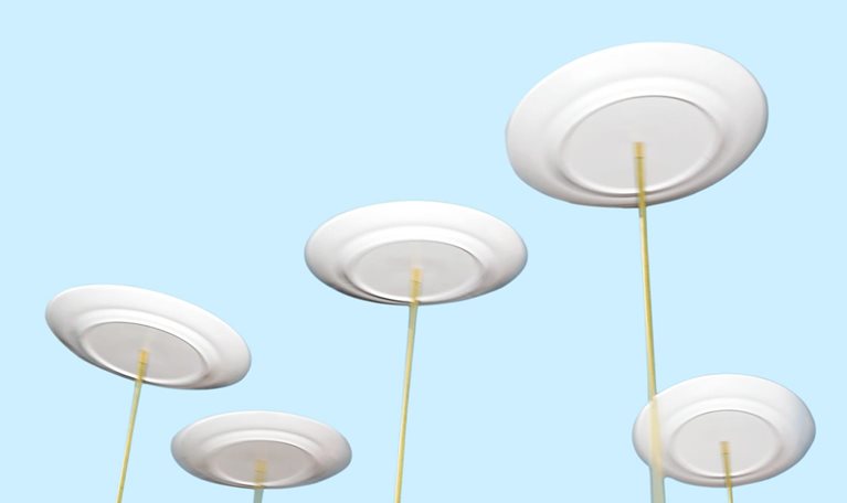 Spinning plates balancing on long poles against a light blue background.