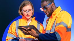 Two manufacturing workers looking at a tablet