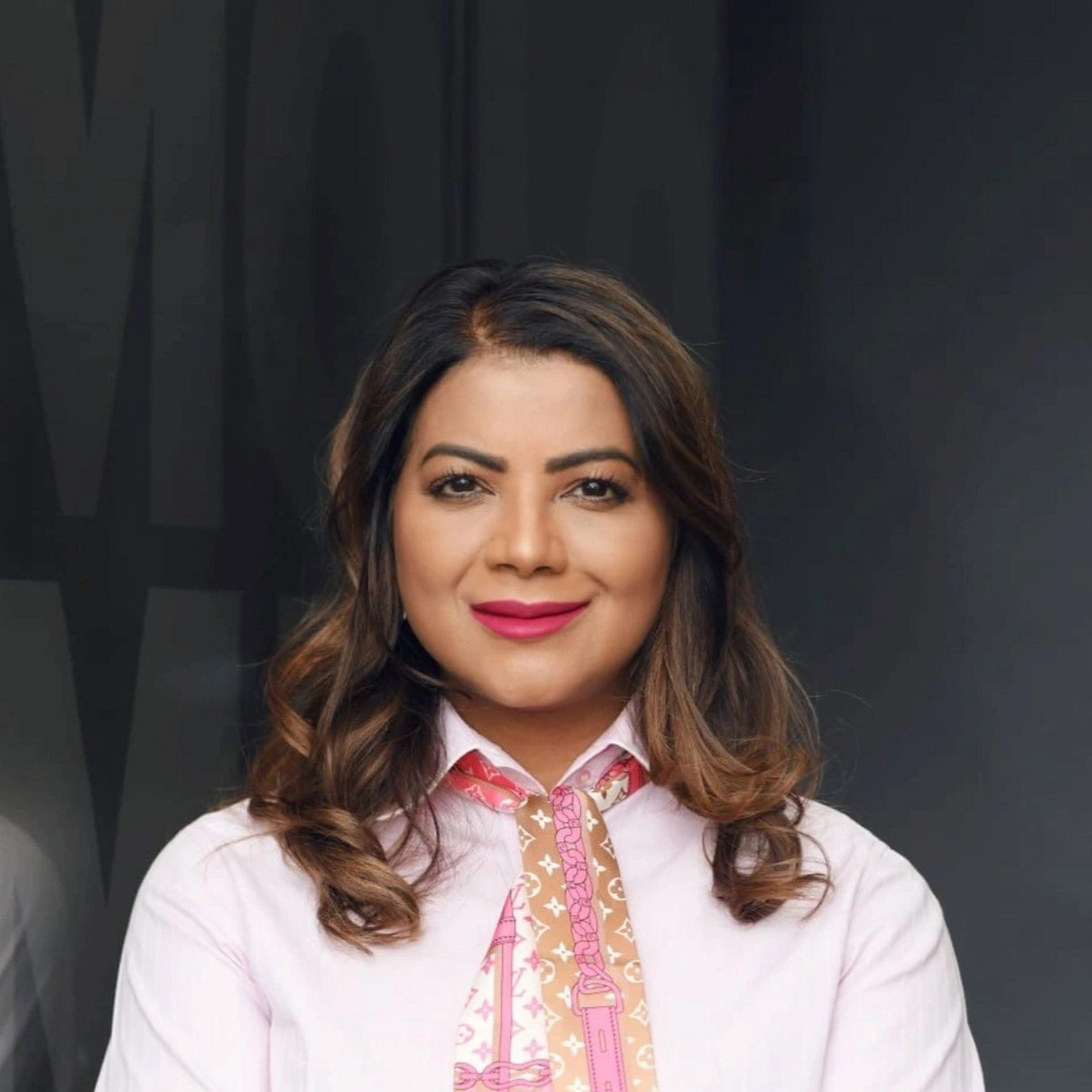 Jeniffer Ramnath with a light smile and wearing a pink top and patterned scarf. 