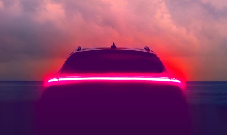 Brake lights glowing on an autonomous vehicle with a hazy blue sky in the background