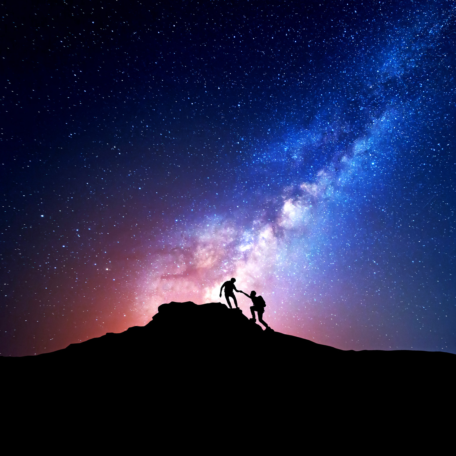 Silhouette of people climbing mountain at night