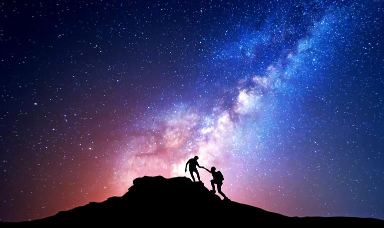 Silhouette of people climbing mountain at night