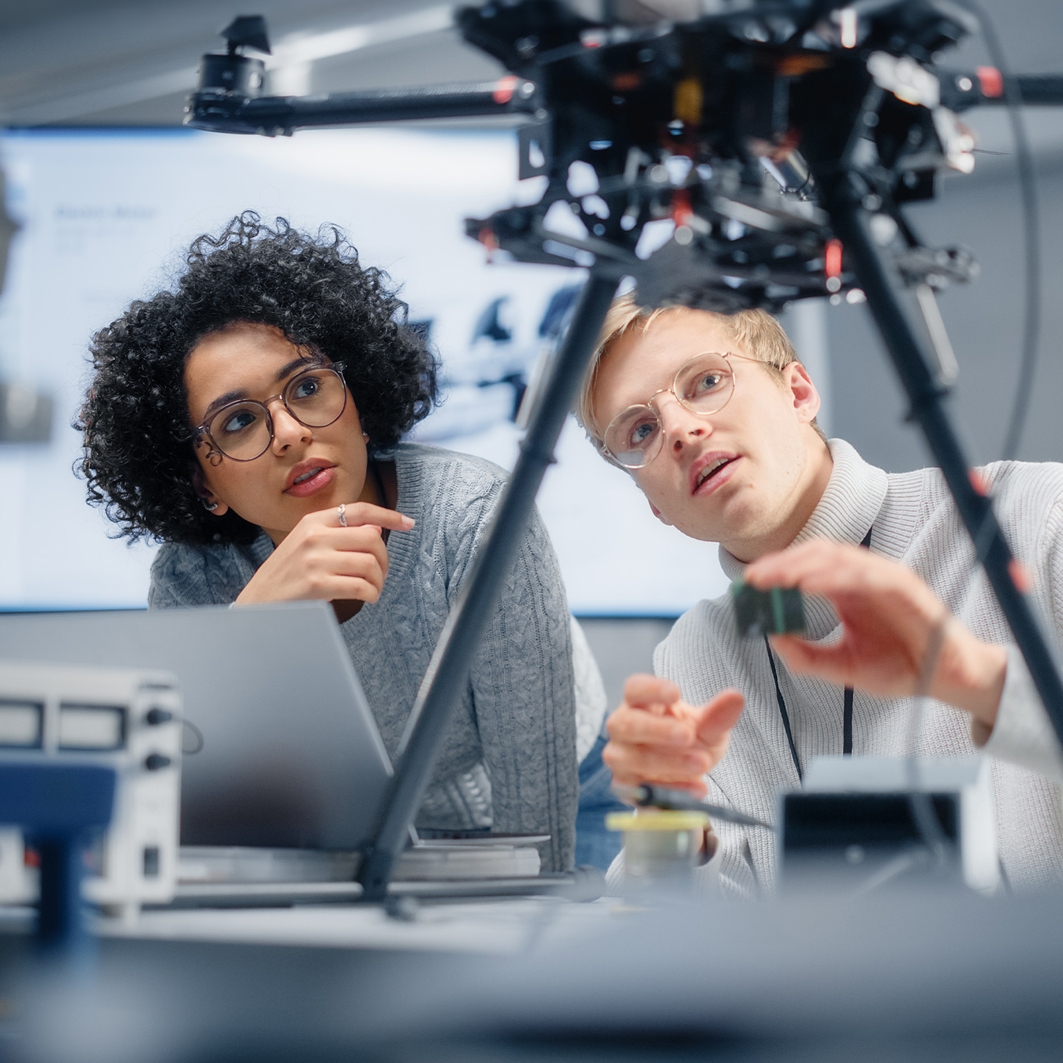 Two diverse developers brainstorming and programming, working together on a new drone.