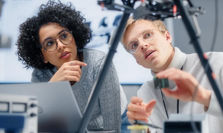 Two diverse developers brainstorming and programming, working together on a new drone.