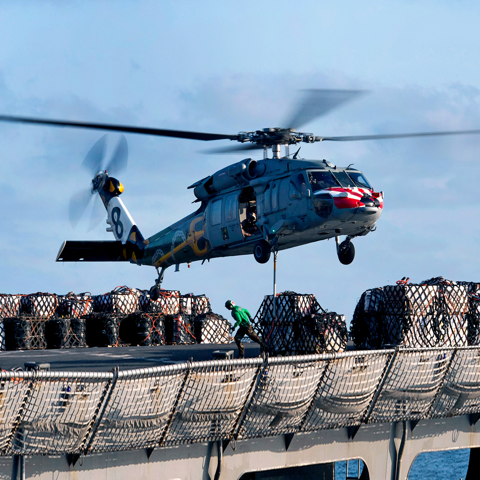 An MH-60S Sea Hawk helicopter lifts cargo from the fast combat support ship USNS Rainier